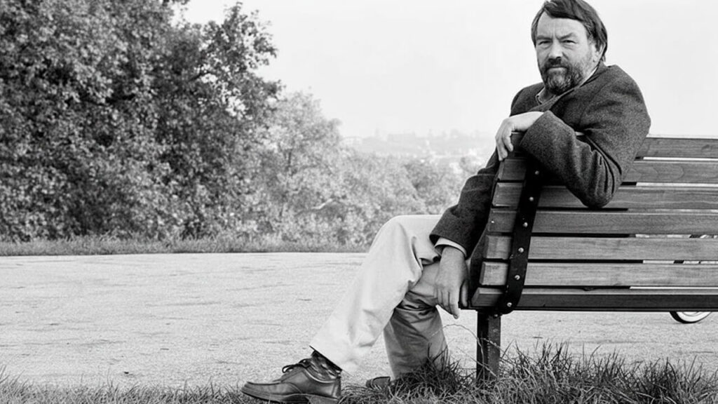 John Fowels posa en su Inglaterra natal en un campo arbolado