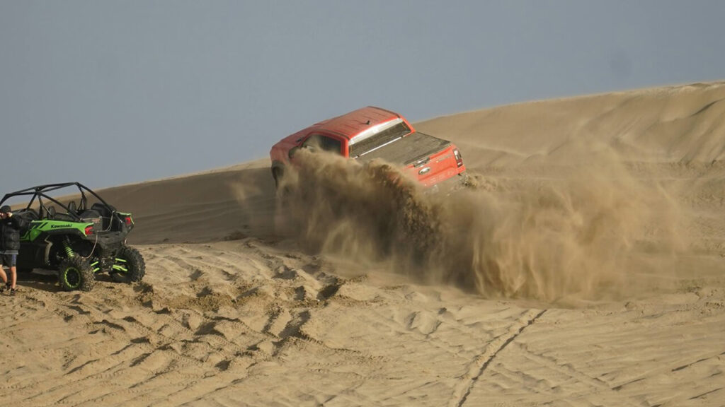 Una Amarock trepadora pasa cerca de un UTV sin pensar en que puede debarrancar