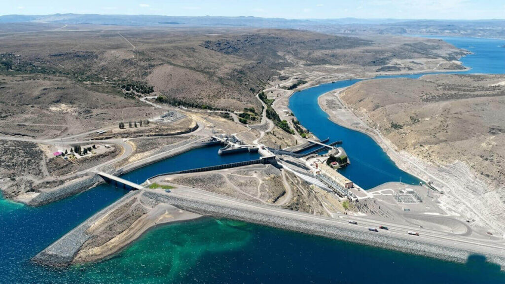 Vista aérea del complejo hidroeléctrico Alicurá sobre el río Limay: se observan el dique, la casa de máquinas, el embalse y el sistema de descarga que regula el caudal aguas abajo.