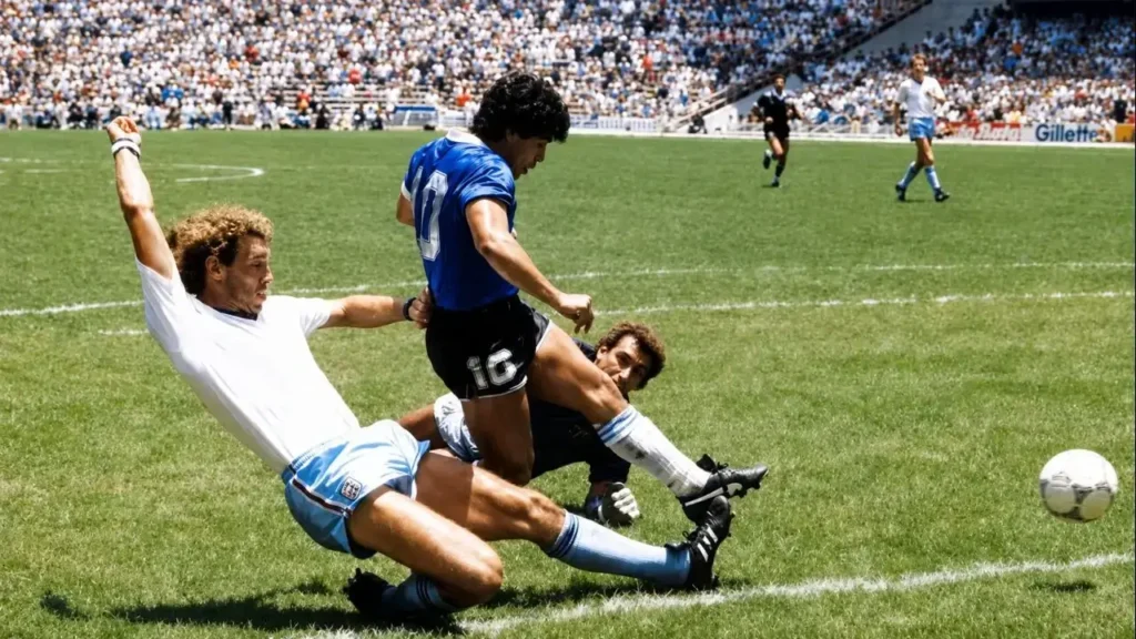 La imagen muestra una de las jugadas más recordadas del fútbol mundial: Diego Armando Maradona encarando dentro del área durante el partido entre Argentina e Inglaterra por los cuartos de final del Mundial de México 1986, disputado el 22 de junio de 1986 en el Estadio Azteca.