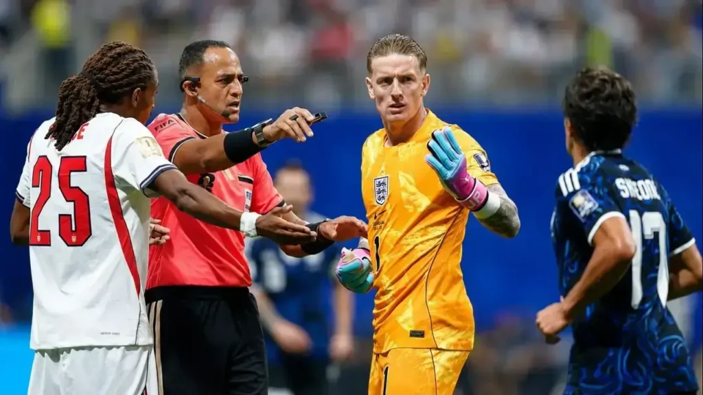 ordan Pickford reclama una decisión arbitral ante la mirada del juez, acompañado por Marc Guéhi, mientras Emiliano "Dibu" Martínez observa la escena desde el área argentina. La intensidad del encuentro también se trasladó a los diálogos con el árbitro durante una semifinal cargada de emociones.