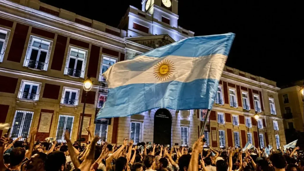 La imagen muestra la Puerta del Sol, en el centro de Madrid (España).

El edificio que aparece al fondo es la Real Casa de Correos, reconocible por su característica torre con reloj. Actualmente es la sede de la Presidencia de la Comunidad de Madrid.