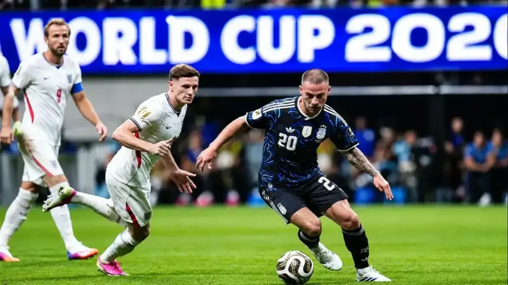 Alexis Mac Allister conduce el balón y acelera el ataque de la Selección Argentina mientras un defensor de Inglaterra intenta darle alcance. Al fondo acompaña la jugada Harry Kane (9), durante un pasaje de alta intensidad de la semifinal del Mundial 2026.