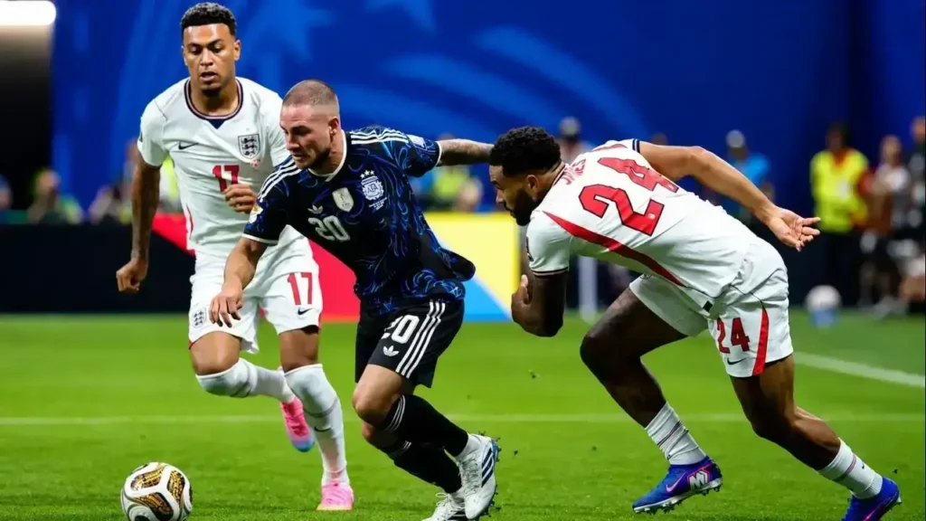 Alexis Mac Allister conduce la pelota entre la presión de Curtis Jones (17) y Reece James (24), que intentan cerrarle los espacios para recuperar el balón. El mediocampista de la Selección Argentina logra salir de la doble marca durante una intensa acción de la semifinal del Mundial 2026 frente a Inglaterra.