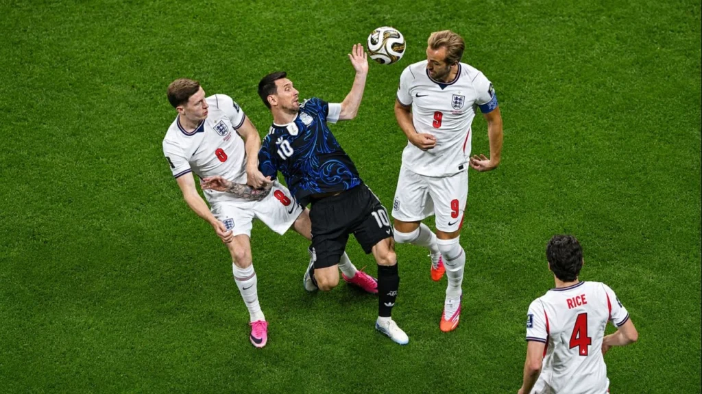 Lionel Messi disputa una pelota aérea rodeado por Elliot Anderson (8) y Harry Kane (9), mientras Declan Rice (4) sigue la acción desde unos metros más atrás. El capitán argentino enfrenta una férrea marca inglesa durante la semifinal del Mundial 2026.