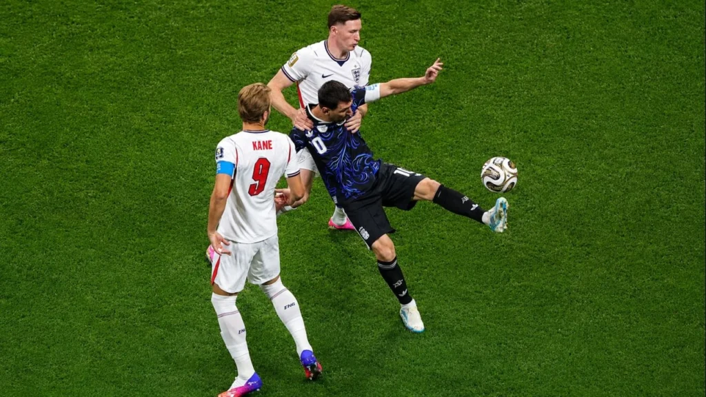 Lionel Messi intenta controlar la pelota mientras recibe la marca de Elliot Anderson (8) y la presión de Harry Kane (9). El capitán de la Selección Argentina vuelve a quedar rodeado por dos futbolistas ingleses en una de las acciones más disputadas de la semifinal del Mundial 2026.