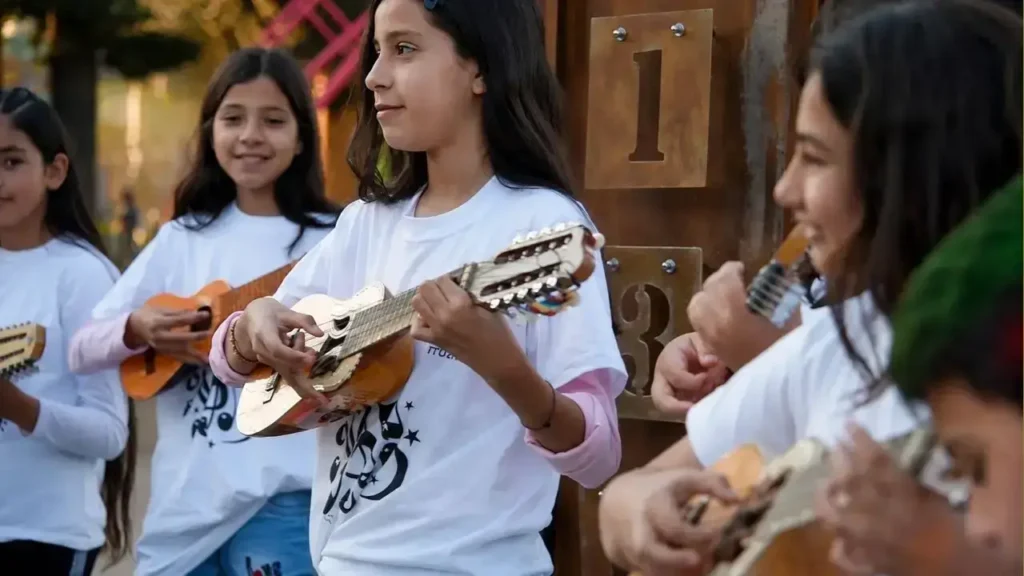 Melodías que nacen del charango: una integrante de la orquesta, concentrada, toca su instrumento con destreza.
