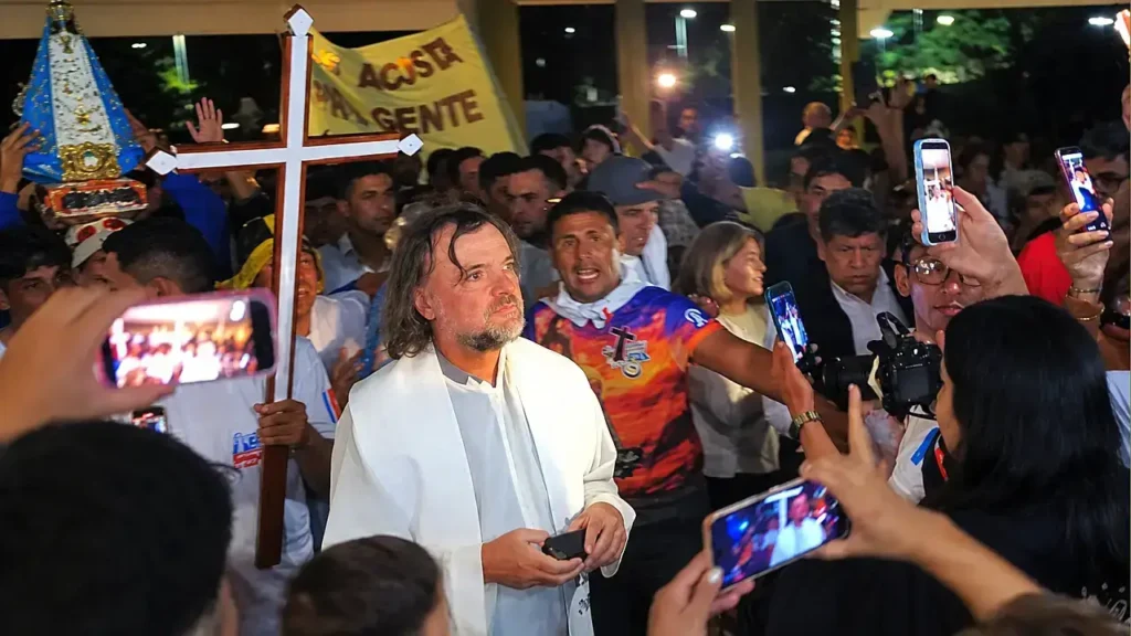 El Padre Pepe di Paola es rodeado por fieles que buscan retratar el momento con sus teléfonos celulares durante un encuentro religioso. 