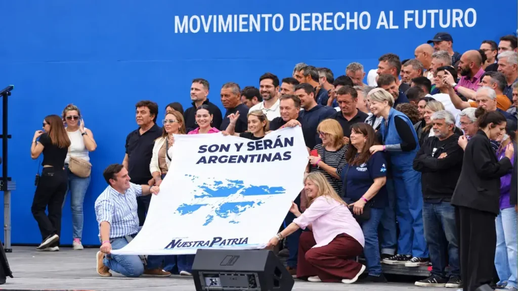 Dirigentes y funcionarios despliegan en el escenario una bandera con el mapa de las Islas Malvinas y la frase "Son y serán argentinas".