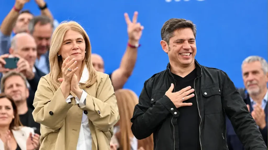 Verónica Magario aplaude a un costado mientras Axel Kicillof, sonriente y con la mano en el pecho, agradece el respaldo de los simpatizantes.