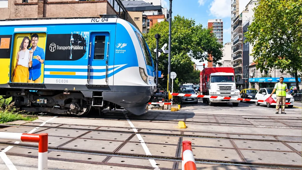 Paso a nivel con banderillero y formación RC 04. Operativo de emergencia con banderillero manual para coordinar el paso de camiones y colectivos ante el cruce de una formación de la Línea Sarmiento.