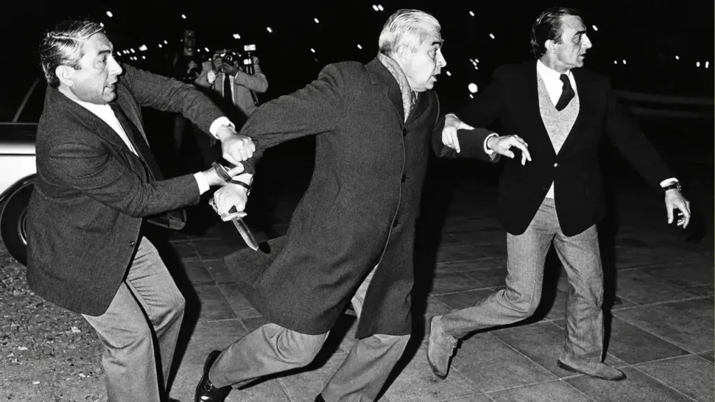 La foto original en blanco y negro de Luciano Benjamín Menéndez conocido como "La Hiena de la Perla". Intentó avalanzarse sobre un grupo de Maddres de Plaza de Mayo y jóvenes que lo insultaban. El logro de la foto es de Enrique Rosito - de Argra.