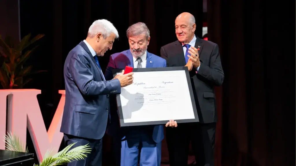 Pablo Navarro (Decano de la Escuela Superior de Leyes), el Juez Federal Jorge Rodríguez y el Rector de la Universidad de Morón, Héctor Porto Lema le entregan una medalla y el título honoris causa.