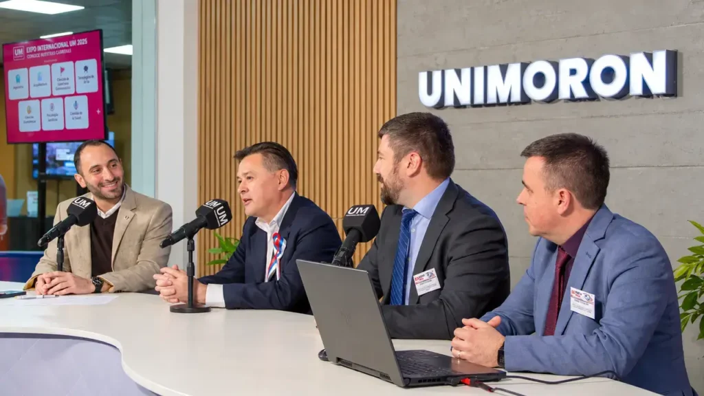 Representantes participan de una charla en la Universidad de Morón. Con micrófonos y una computadora sobre la mesa, los expositores conversan ante el público durante la Expo Internacional UM 2025.