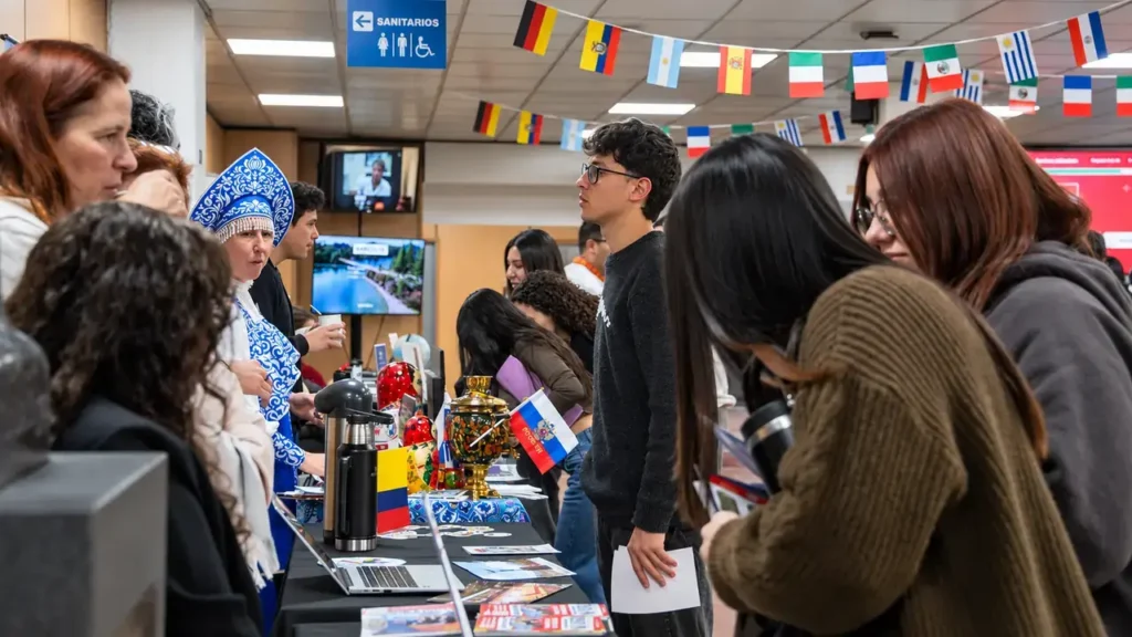 Estudiantes recorren los puestos y consultan a los expositores. En uno de los stands, una representante vestida con indumentaria tradicional rusa conversa con jóvenes durante la feria universitaria.