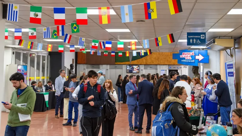 La Expo Internacional UM reúne a estudiantes, instituciones y delegaciones. El pasillo de la Universidad de Morón aparece concurrido, con stands informativos, banderas de distintos países y propuestas para quienes buscan conocer opciones educativas y culturales.