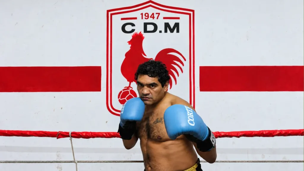 Con los guantes azules en guardia, Castro aparece frente a un escudo del Club Deportivo Morón. La imagen lo retrata en una postura clásica de boxeador y lo vincula visualmente con el distrito donde vivió sus últimos años y donde falleció durante la madrugada del miércoles 14 de octubre.